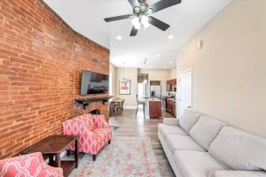 een woonkamer met een bank en een bakstenen muur bij St Louis Townhome Perfect for Groups in Tower Grove