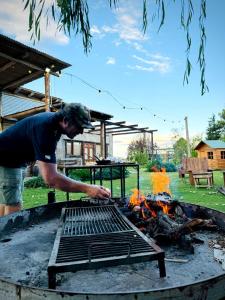 a man standing over a grill with a fire at Finca La Valletana in Vista Flores