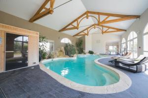 a swimming pool in a house with chairs in it at Hôtel de la Louée in Haute-Goulaine