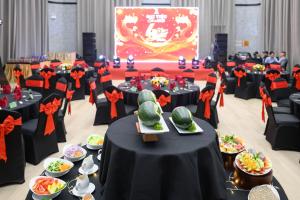 a banquet hall with black tables with plates of food at K-Town Resort Phan Thiet in Phan Thiet