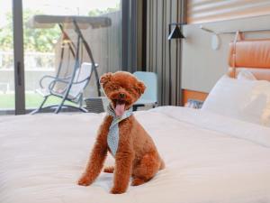 a brown teddy bear wearing a tie sitting on a bed at WM Hotel Hong Kong, Vignette Collection in Hong Kong