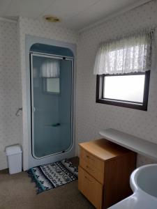 uma casa de banho com uma cabina de duche em vidro e um lavatório. em Denby Golf House Tikipunga em Whangarei
