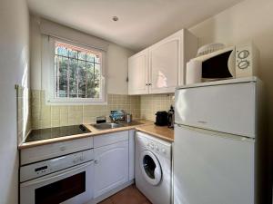 eine Küche mit einem weißen Kühlschrank und einem Geschirrspüler in der Unterkunft Les Issambres : Appt 2 pièces, piscine, clim, pour 4 pers. - FR-1-226-540 in La Garonnette-Plage