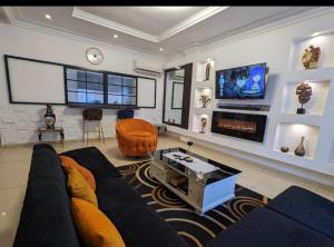 uma sala de estar com um sofá e uma televisão em THE GOLF RESIDENCES YAOUNDE em Iaundé