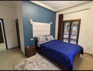 um quarto com uma cama e uma parede azul em THE GOLF RESIDENCES YAOUNDE em Iaundé