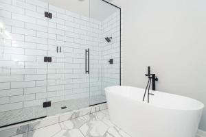 a white bathroom with a tub and a glass shower at Eclectic Stylish and Cozy Milwaukee Home in Milwaukee