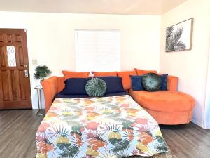 un sofá naranja y una cama en una habitación en 9min to Univ of Redlands Spacious Boho Home 5min to Downtown DISCOUNTS, en Redlands