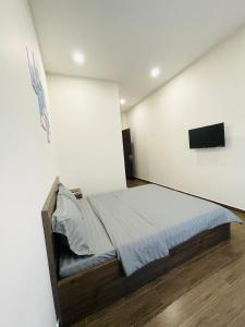 a bedroom with a bed and a flat screen tv at Rio Guest House - Phú Quốc in Phú Quốc