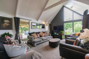 a living room with couches and chairs and windows at Alpine Rock B&B in Te Anau