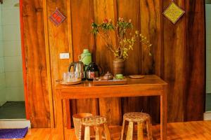 a wooden table with stools and a table with flowers on it at A Dế Homestay Sơn Tra in Phong Thổ