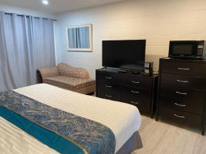 a bedroom with a bed and a tv and a chair at Slumber Lodge in Hope