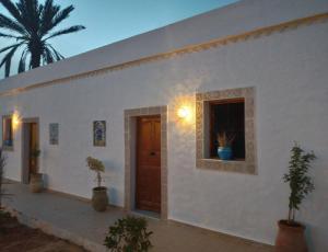 biały budynek z drzwiami i oknem w obiekcie Djerba rêve vacances Zohra w mieście Midun