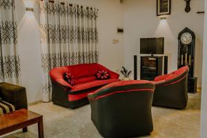 ein Wohnzimmer mit 2 Stühlen und einem roten Sofa in der Unterkunft Lihini Villa ii in Matara