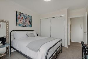 um quarto branco com uma cama e um espelho em Peaceful 1-Bed Apartment Close to Lonsdale St em Camberra