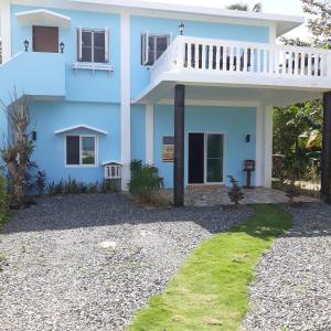 a blue house with a balcony and a gravel yard at Whitesands Beach Resort in San Isidro