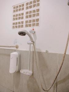 a shower with a hose hooked up to a wall at Angel Home Stay by Nusalink in Warungsergon