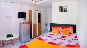 a bedroom with a bed with red and yellow pillows at Angel Home Stay by Nusalink in Warungsergon