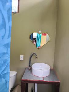 a bathroom with a sink and a heart shaped mirror at Villalu. in Cahuita +25 photos