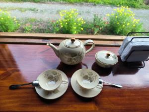 a tea set on a table with two cups and spoons at Villalu. in Cahuita