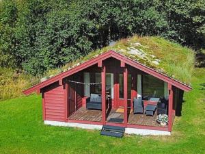 a red building with a grassy roof with chairs and a deck at 6 person holiday home in olden in Olden