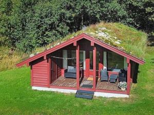a red building with a grassy roof with chairs at 6 person holiday home in olden in Olden