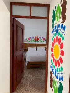 sypialnia z łóżkiem z malowidłem kwiatowym na ścianie w obiekcie PERLASCHALLAY w mieście Ayacucho