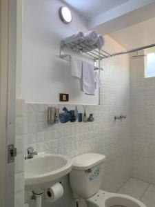 a white bathroom with a toilet and a sink at PERLASCHALLAY in Ayacucho