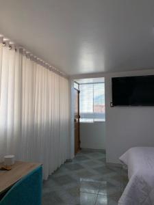 sypialnia z łóżkiem i telewizorem z płaskim ekranem w obiekcie PERLASCHALLAY w mieście Ayacucho