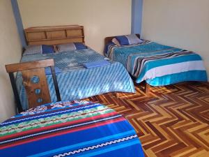 a room with two beds and a wooden floor at Departamento Las Malvinas Puno in Puno