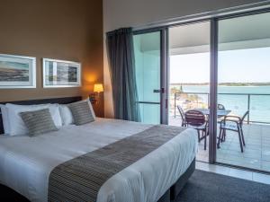 巴利纳Ramada Hotel & Suites by Wyndham Ballina Byron的一间带床的卧室和一个带桌子的阳台