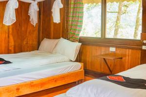 two beds in a room with a window at A Dế Homestay Sơn Tra in Phong Thổ