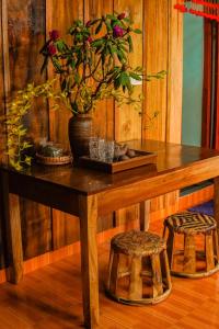 a wooden table with a potted plant and two stools at A Dế Homestay Sơn Tra in Phong Thổ
