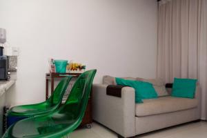 a living room with a couch and green chairs at Flat no Nannai Residence Muro Alto in Porto De Galinhas