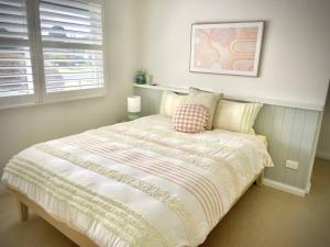 ein Schlafzimmer mit einem Bett mit einer Decke und einem Fenster in der Unterkunft River Front on Hennessy in Tocumwal