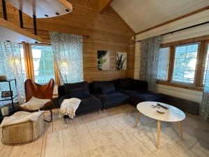 een woonkamer met een zwarte bank en een tafel bij Upea villa lähellä rantaa poreallas & SUP-laudat in Vaasa