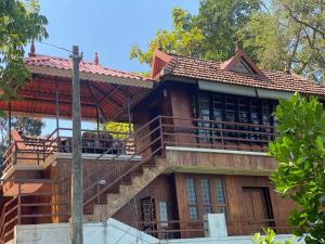 a wooden house with a balcony and stairs at Mayoorapanjaram in Neyyāttinkara