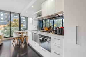 - une cuisine avec des placards blancs, une table et des chaises dans l'établissement 2-Bed Inner-City Pad Bright with Panoramic Views, à Melbourne