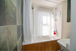 a bathroom with a shower curtain and a window at Refurbished Double Bedroom in London
