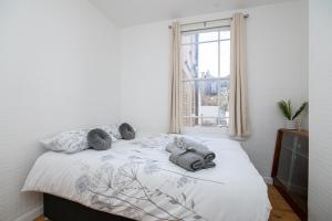 a white bedroom with a large bed with a window at Refurbished Double Bedroom in London