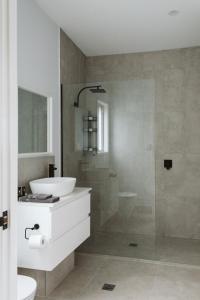une salle de bain avec un lavabo blanc et une douche dans l'établissement Wallaby 3-Bedroom at On Burgum Pond Cottages, à Maleny 38 autres photos