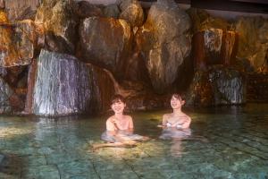 two boys sitting in the water in a waterfall at Ooedo Onsen Monogatari Premium Kinugawa Kanko Hotel in Nikko