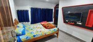 a bedroom with a bed with a tv and blue curtains at Hotel Shree Sai in Daringbadi
