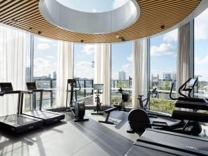 a gym with treadmills and ellipticals in a room with windows at Modern 2B APT BayViews*Pool*GYM in Melbourne