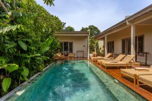 a swimming pool with chairs and a house at RIYURI GUESTHOUSE in Tumbak Bayuh