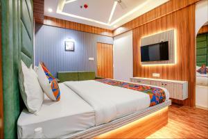 a bedroom with a large bed and a television at FabHotel Max in Vadodara