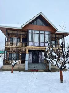 une maison en rondins avec de la neige devant elle dans l'établissement Hideaway Cottages , Tangmarg, à Tangmarg