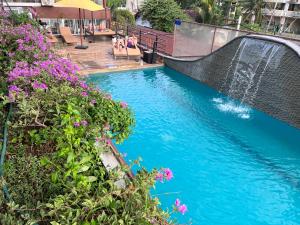 尼甘布Beach Corridor Hotel & Spa with Free Airport shuttle的一座带瀑布和紫色鲜花的游泳池