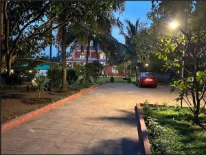 a red car parked in a driveway in front of a house at The Chapters Villa in Alibag