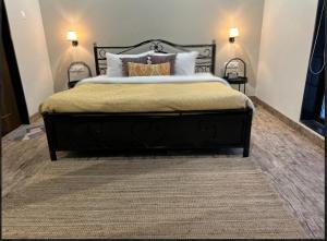 a bedroom with a large black bed with two lamps at The Chapters Villa in Alibag