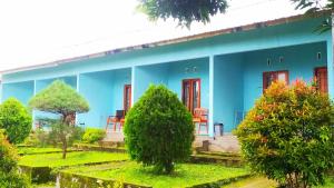 un edificio azul con puertas rojas y sillas en un jardín en Embun Rinjani Homestay, en Senaru